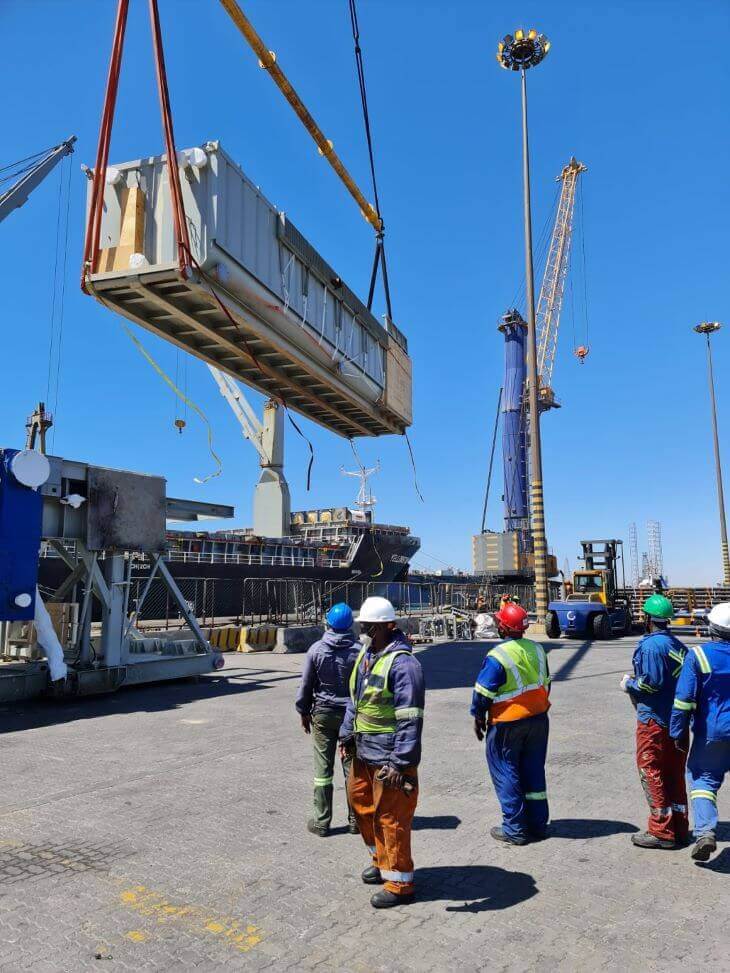 Workers looking at the container being lifted by the crane