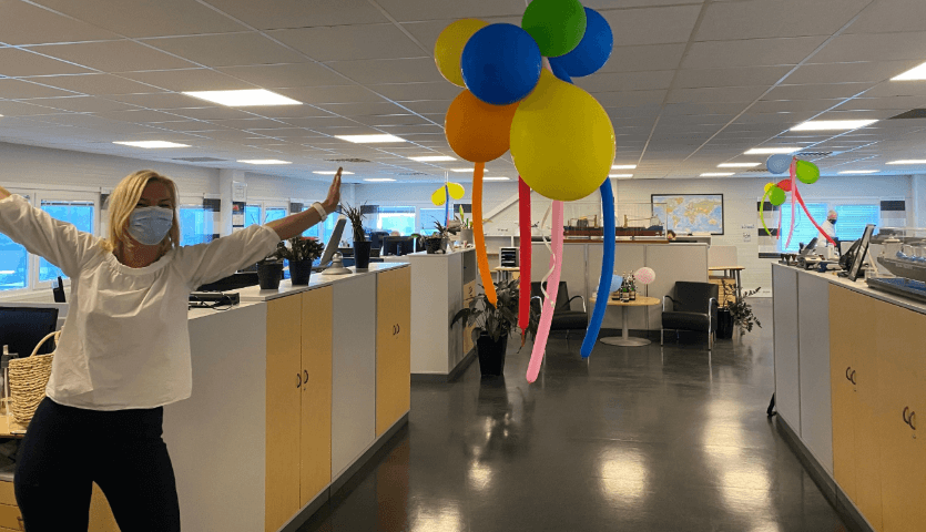 A woman in a protective mask against the background of colorful balloons in the office