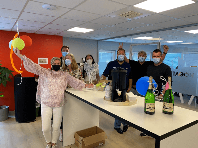 Group of people in a protective masks celebrating in the office