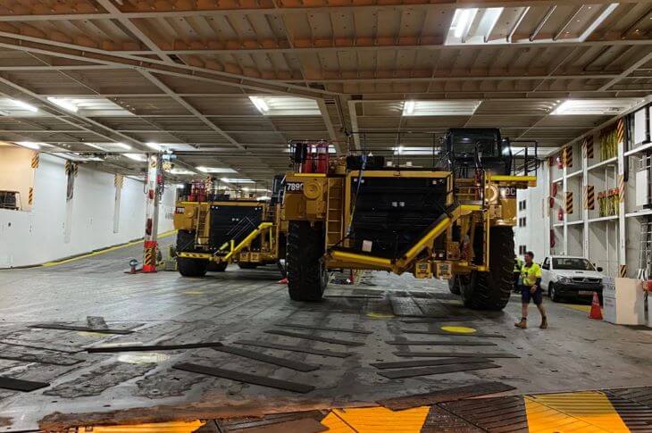 Two giant dump trucks in warehouse