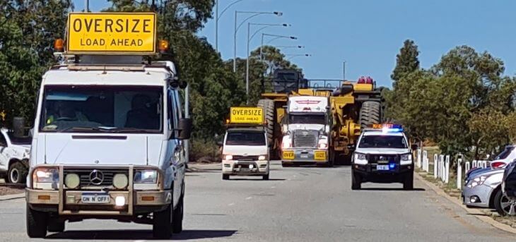 Transport of giant dump trucks in escort of special vehicles