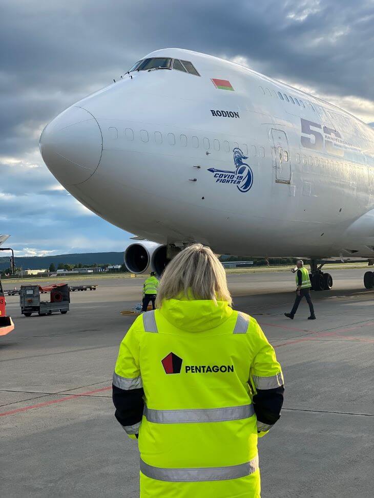 A woman in a yellow jacket with the Pentagon logo on the background of a large plane