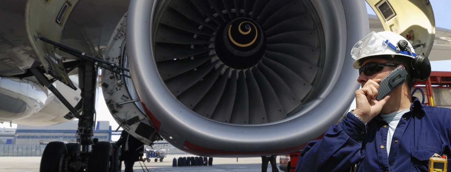 Worker in a helmet next to an airplane turbine