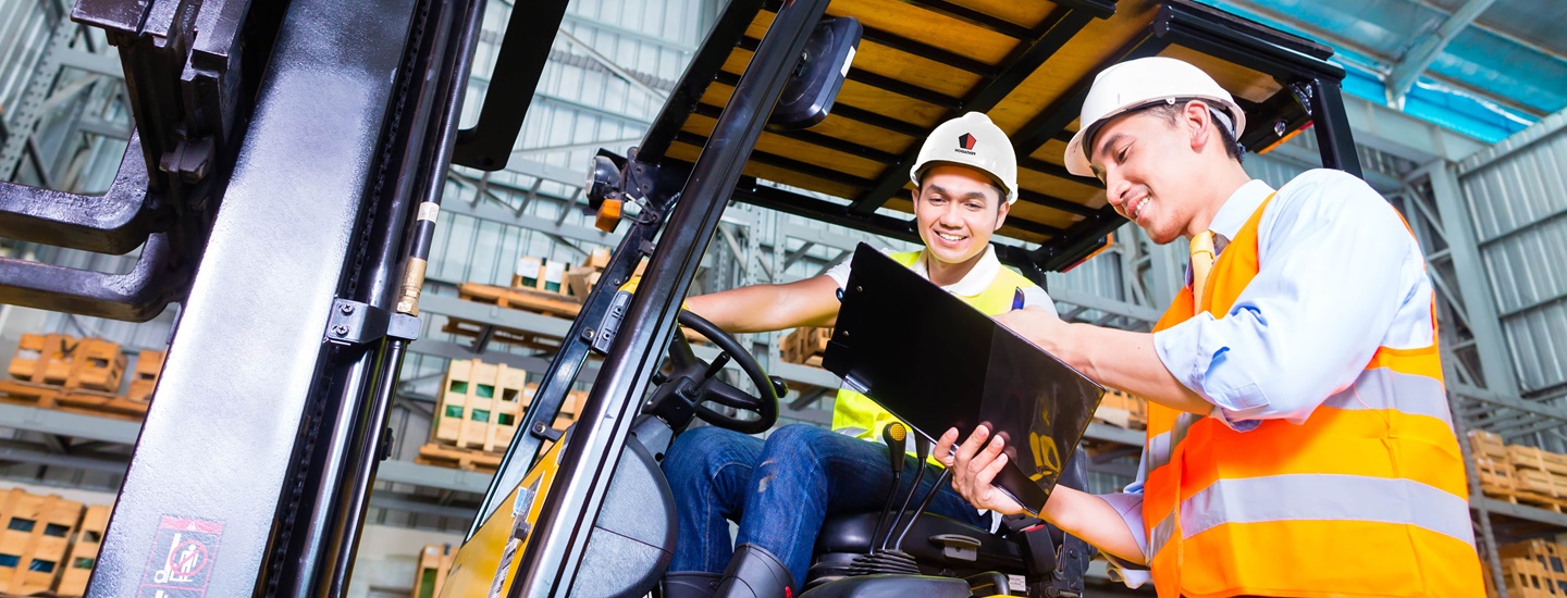 Workers in helmets working on a forklift