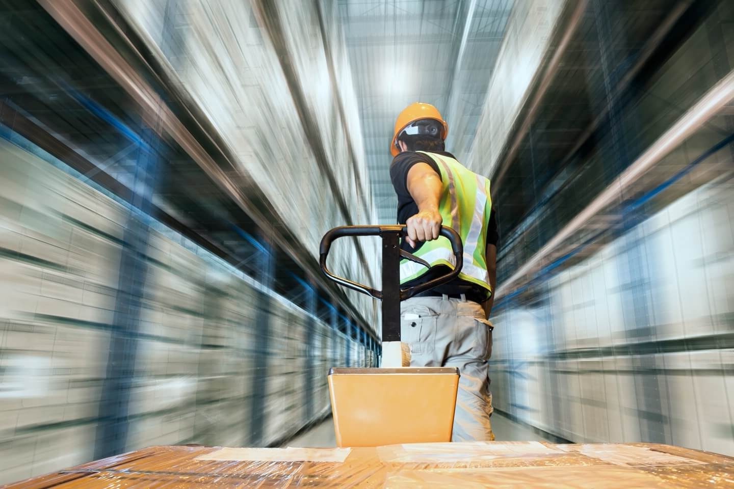 A warehouse worker pulls a pallet truck