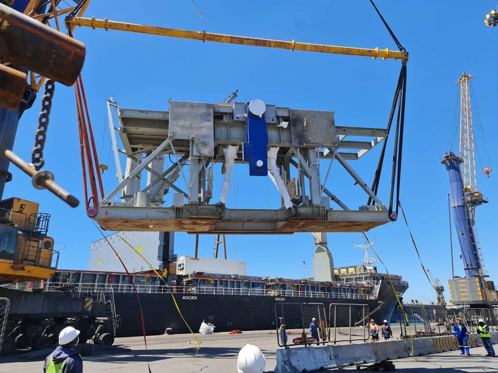 Crane lifting a large iron machine in the port