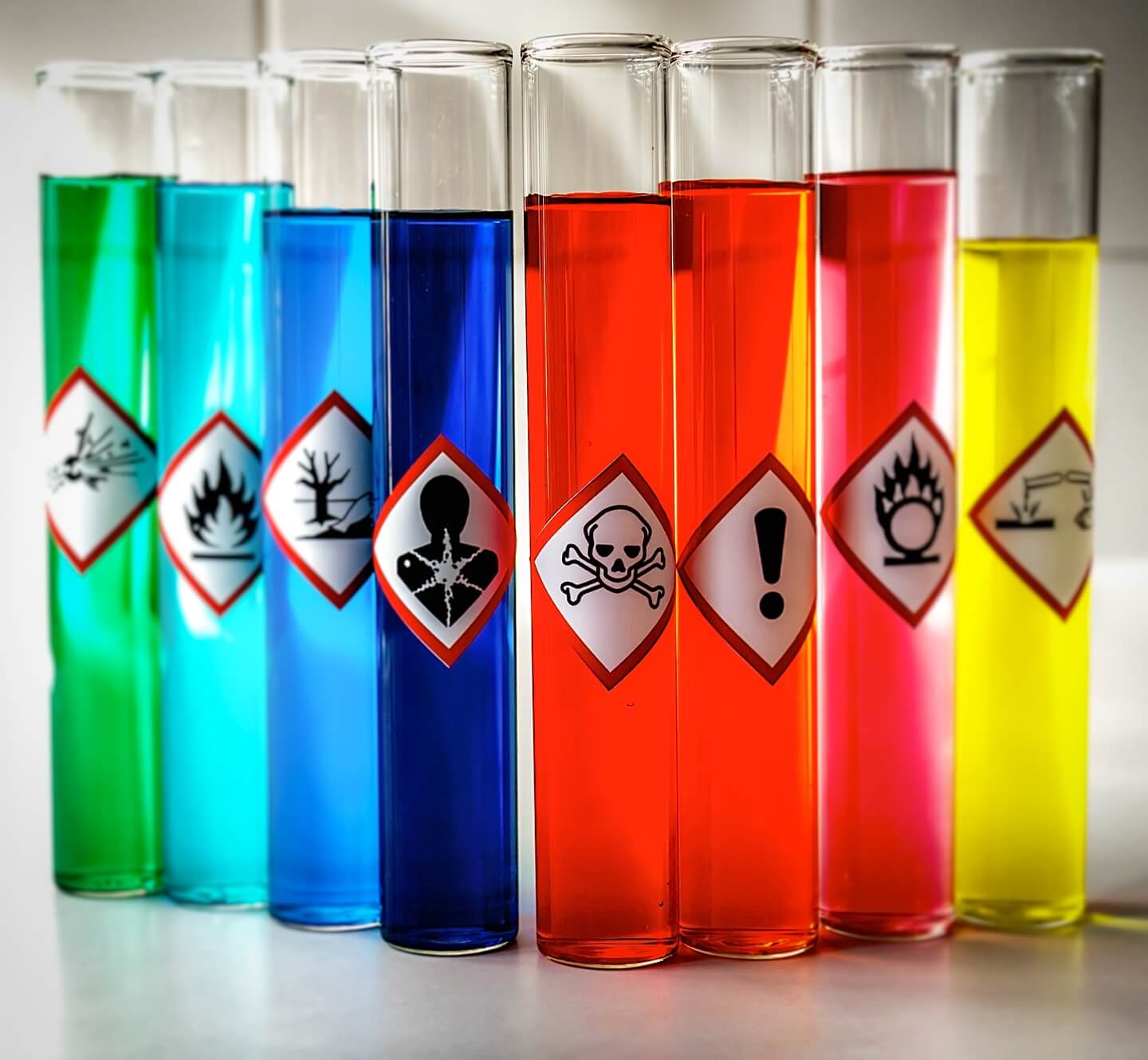 Vials of colored dangerous substances with attached warning pictograms