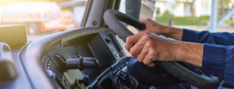 The man is holding his hands on the steering wheel of the truck