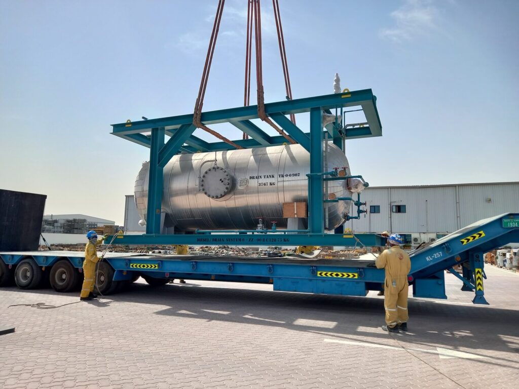 Employees help with the transport of the large tank