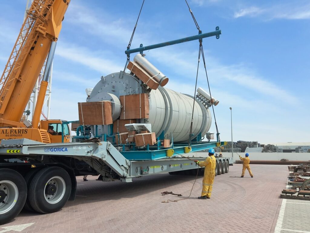 Employees help with the transport of the large tank