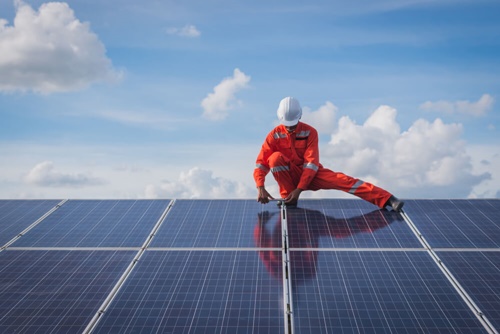 Worker in a helmet installs solar panels