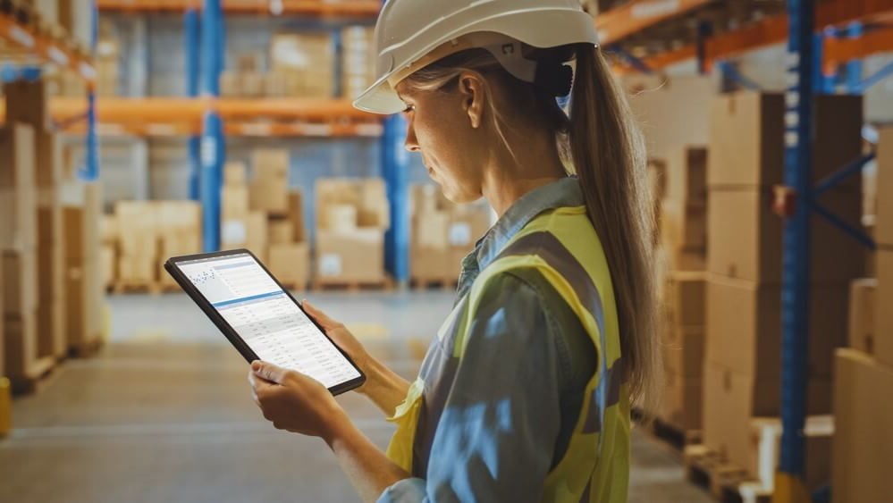 A woman in a protective helmet is holding a tablet in her hands