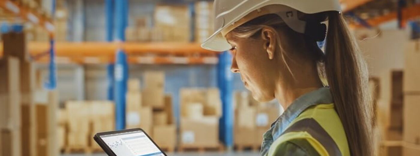 A woman in a protective helmet is holding a tablet in her hands